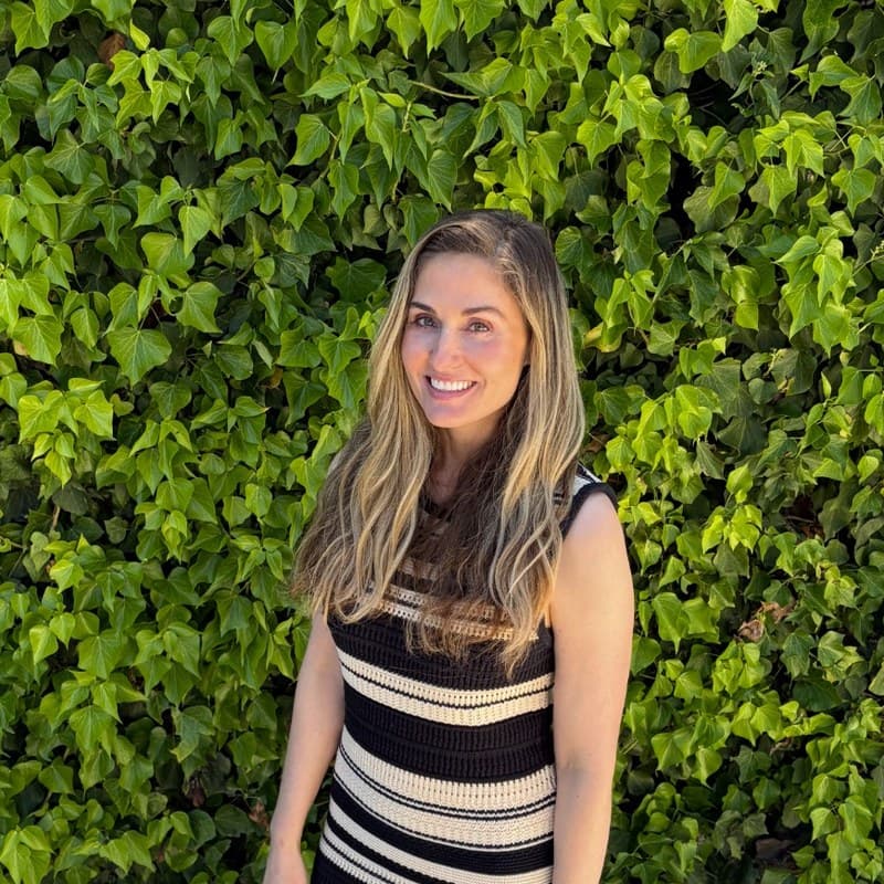 Bevens Goodman standing in front of a leafy green wall